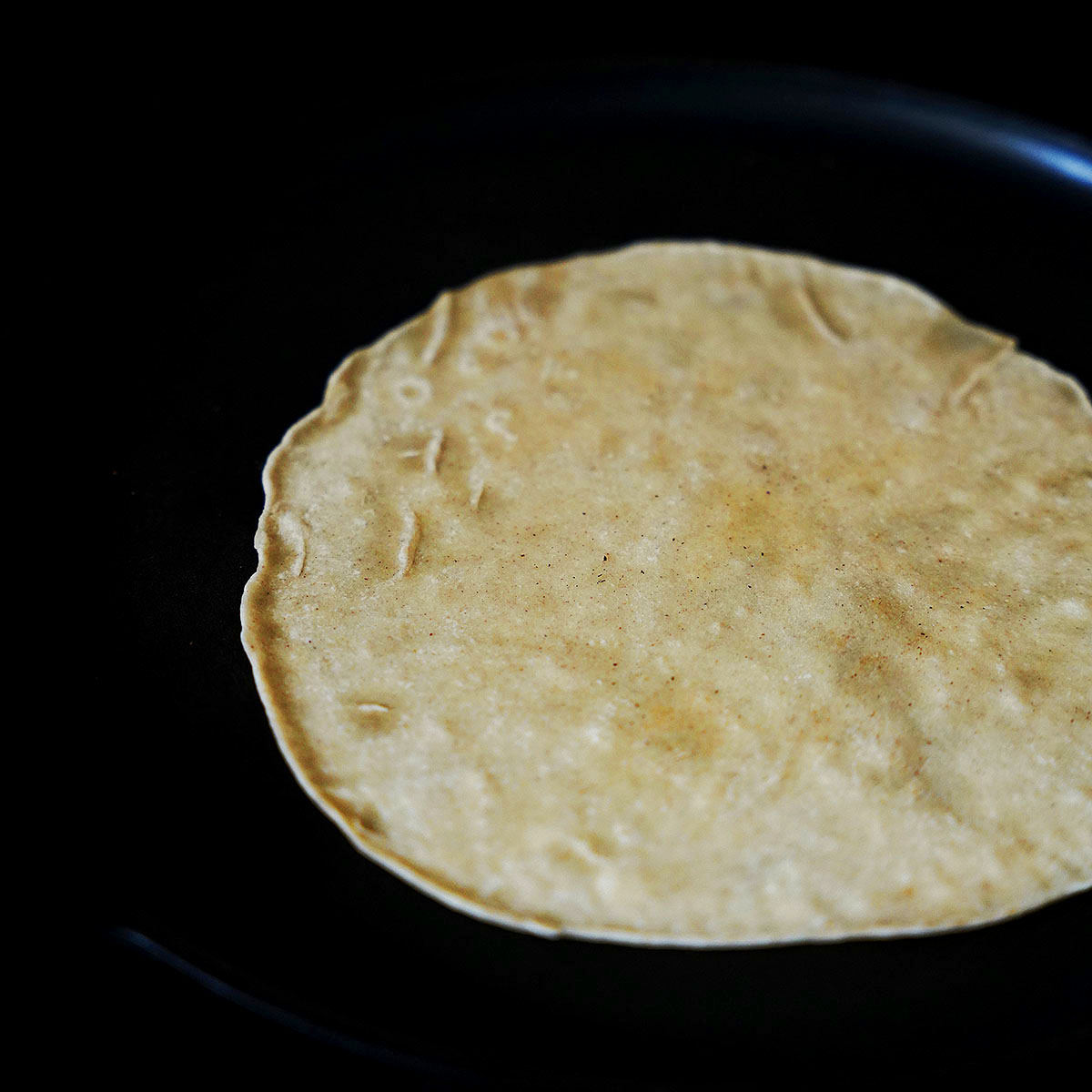 Cooking the dough disk on a skillet.