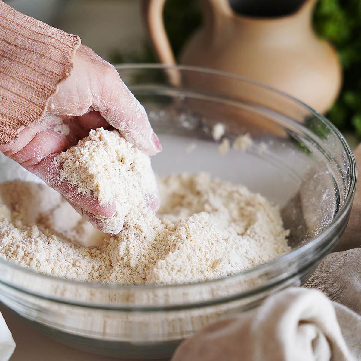 A hand mixing the flour in a bowl.
