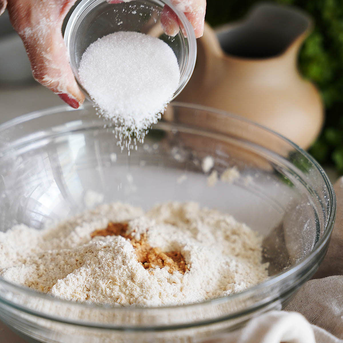 Adding sugar into a bowl with flour.