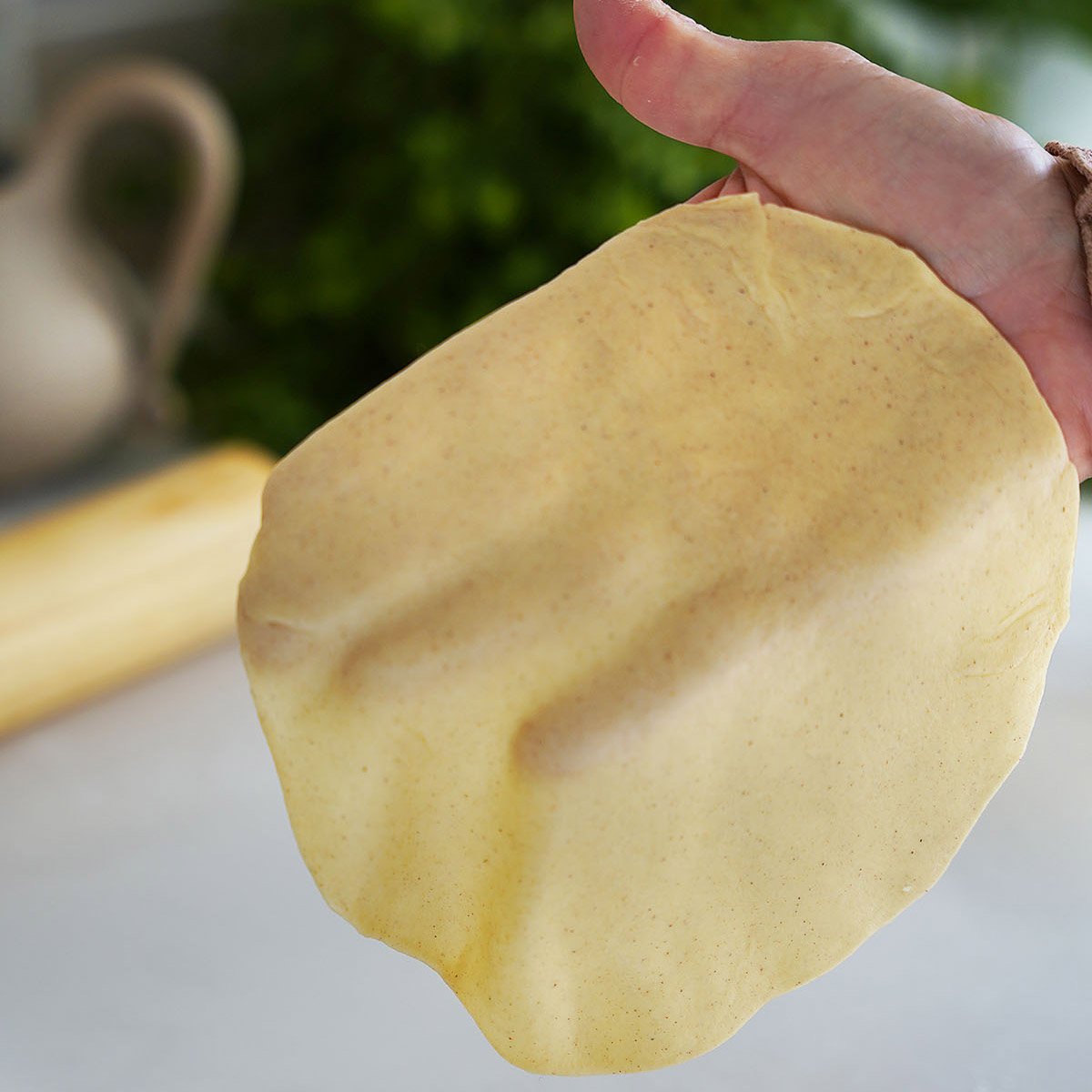 A hand holding the flattened dough.