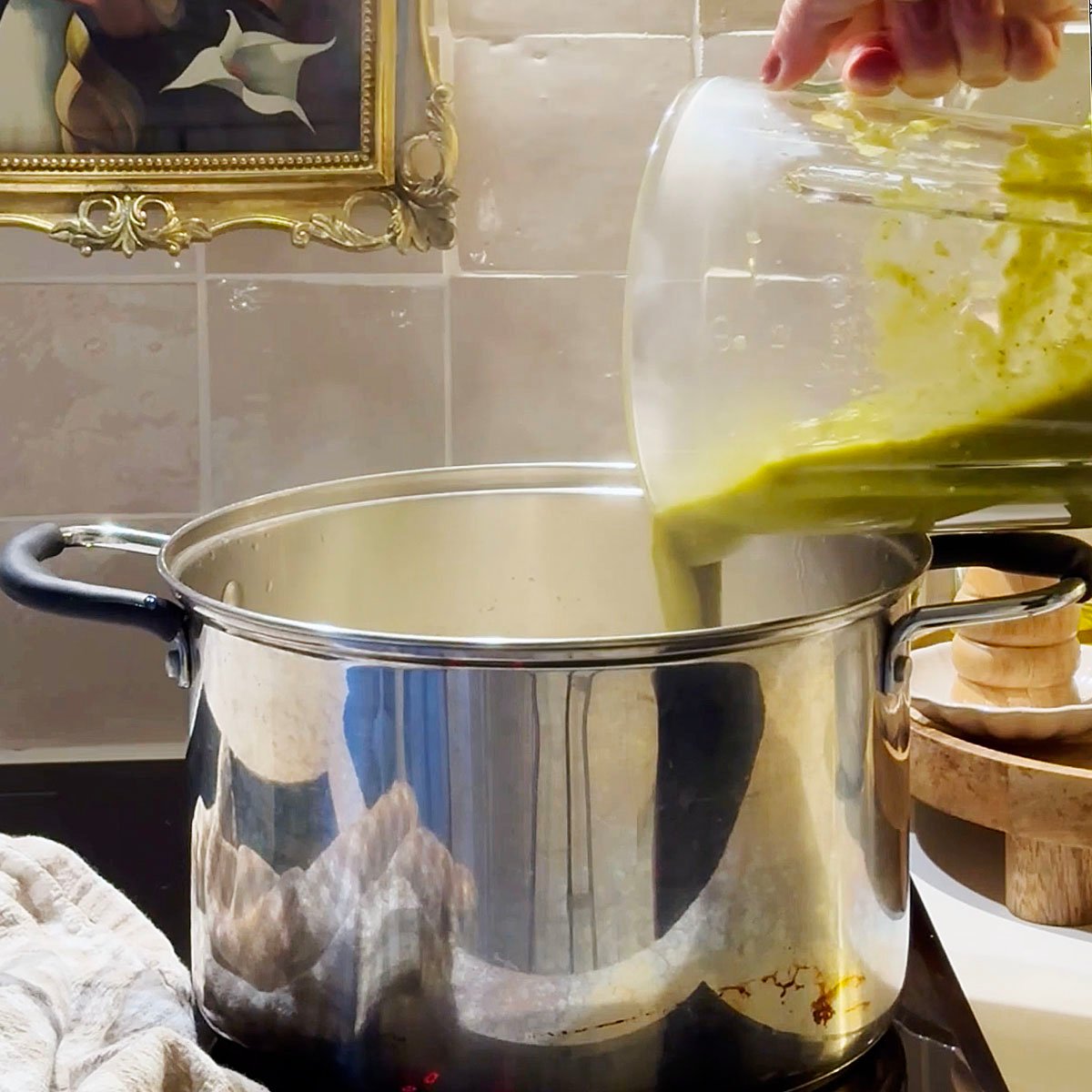Pouring salsa verde into a large pot.
