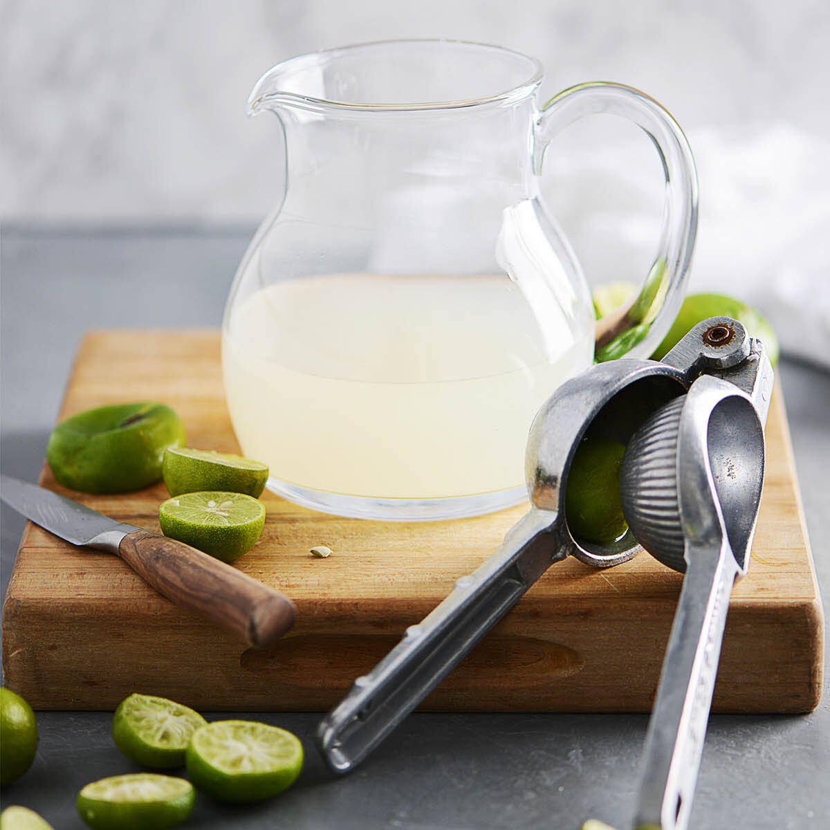 A glass jar half filled with lime juice and squeezed limes on the side.