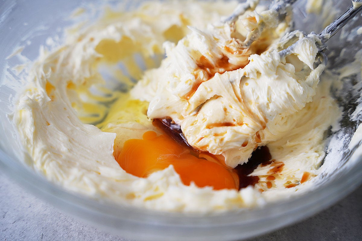 A bowl with whipped butter, one egg and vanilla extract.