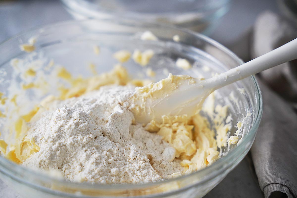 A glass mixing bowl with whipped butter and flour.