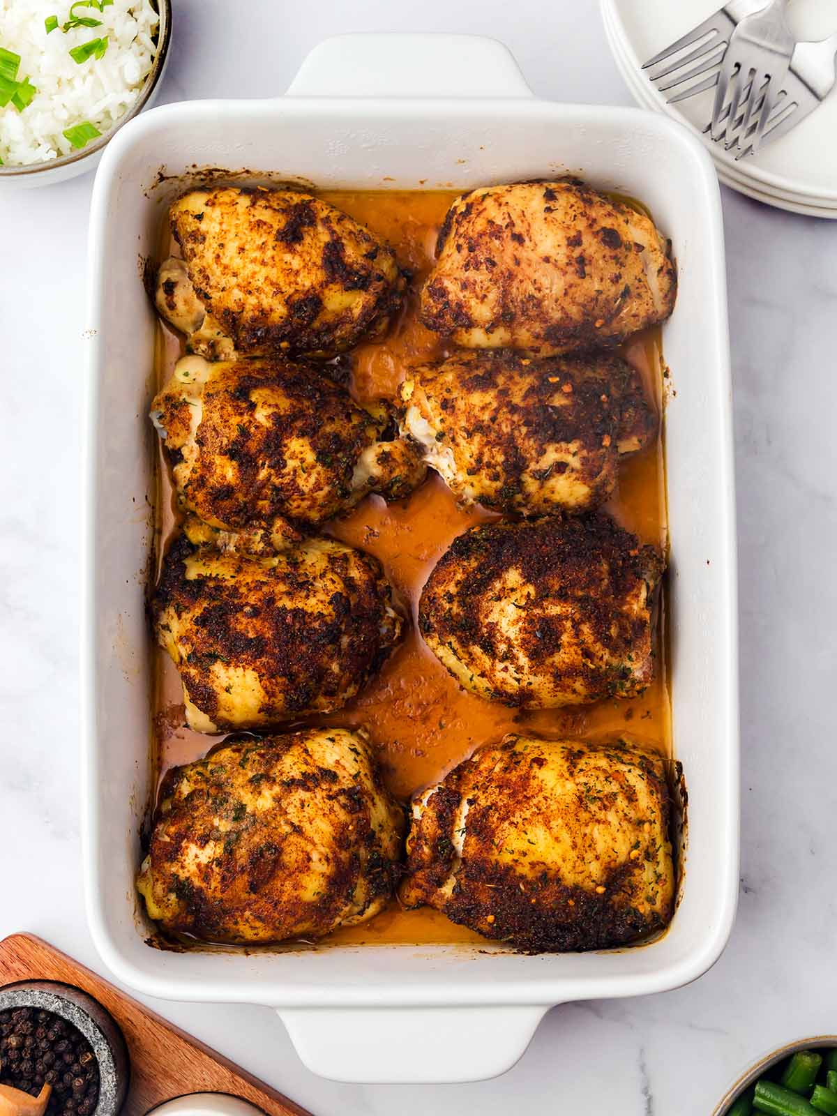 Pollo Al Horno in a baking dish with plates on the side.