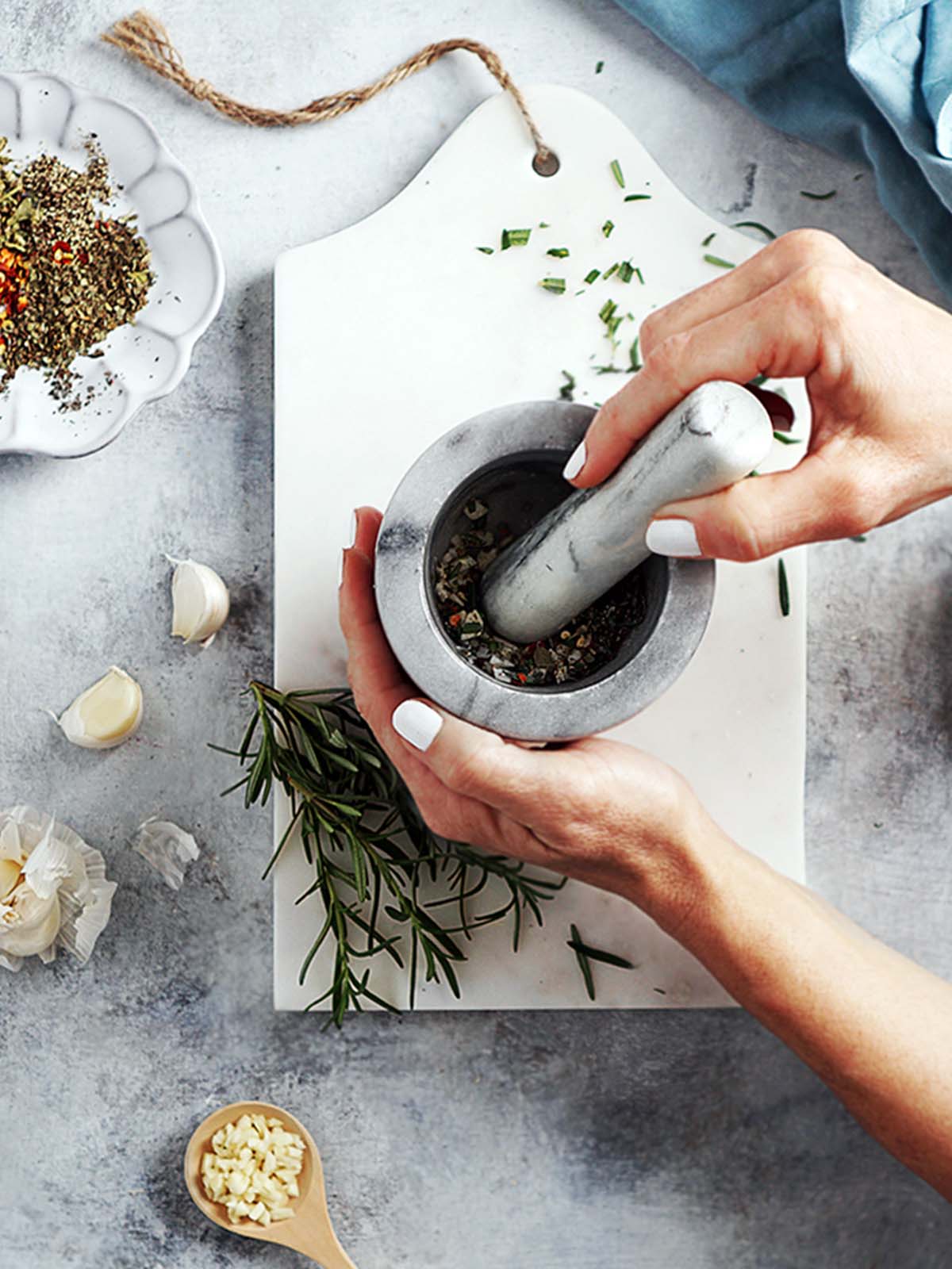 Two hands holding a pestle and mortar grinding herbs.