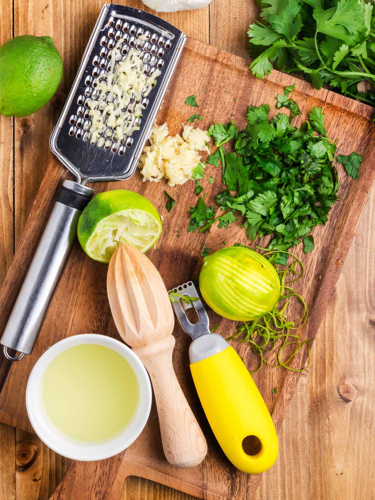 Zesting limes and chopped cilantro on a chopping board.