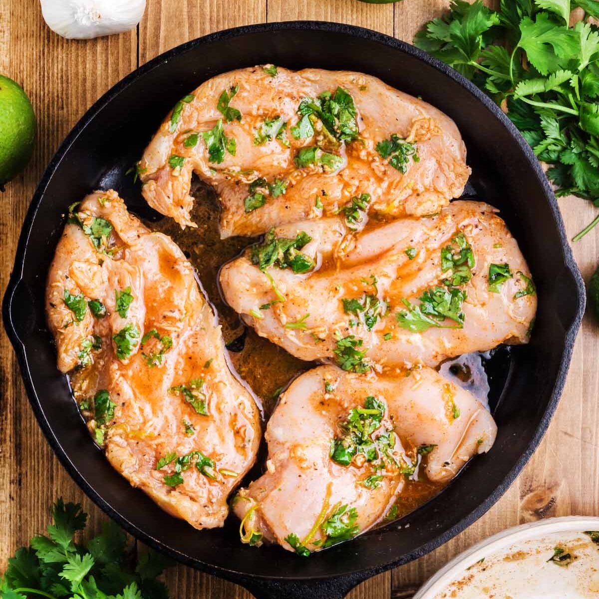 A skillet with raw chicken breast.