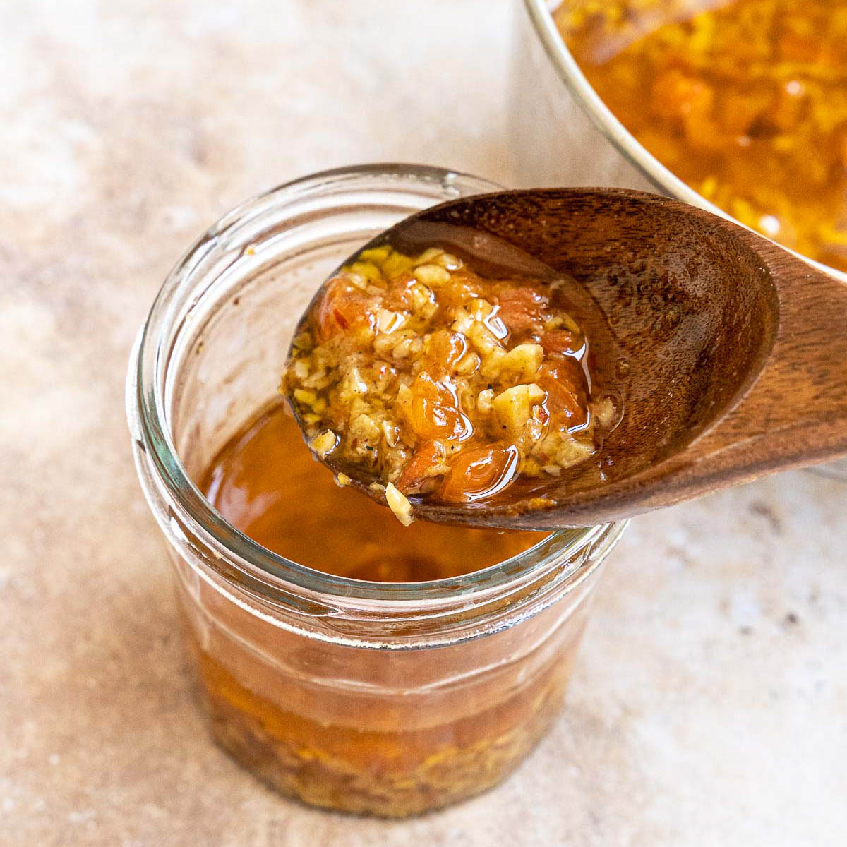 A jar of with mojo de ajo and a wood spoon.