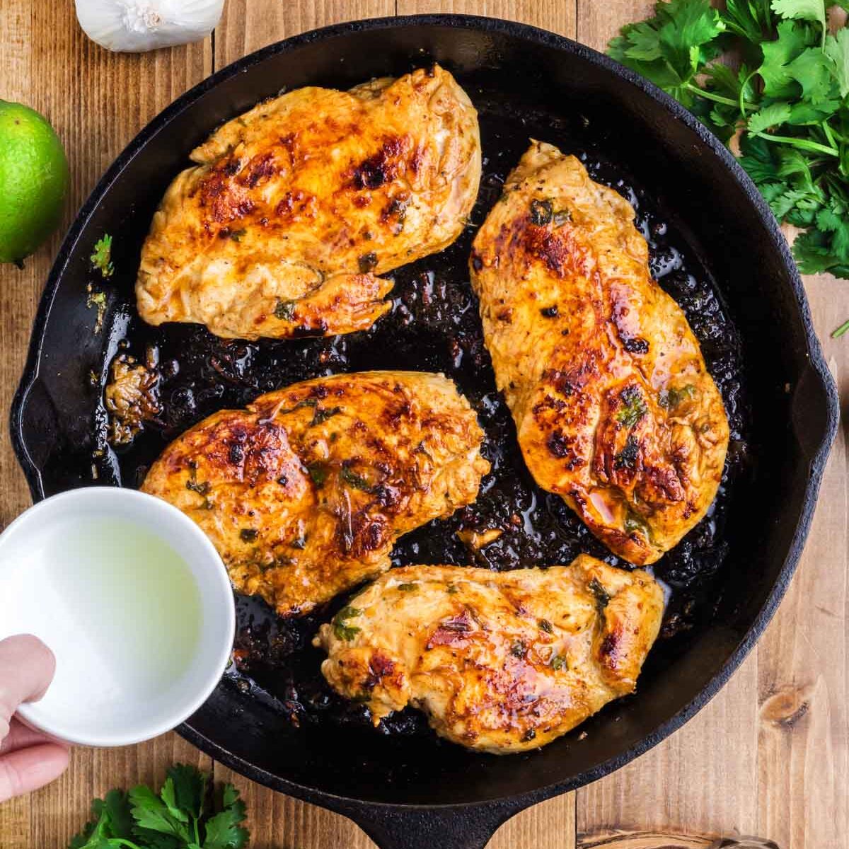 A skillet with cooked chicken breast and adding lime juice to it.