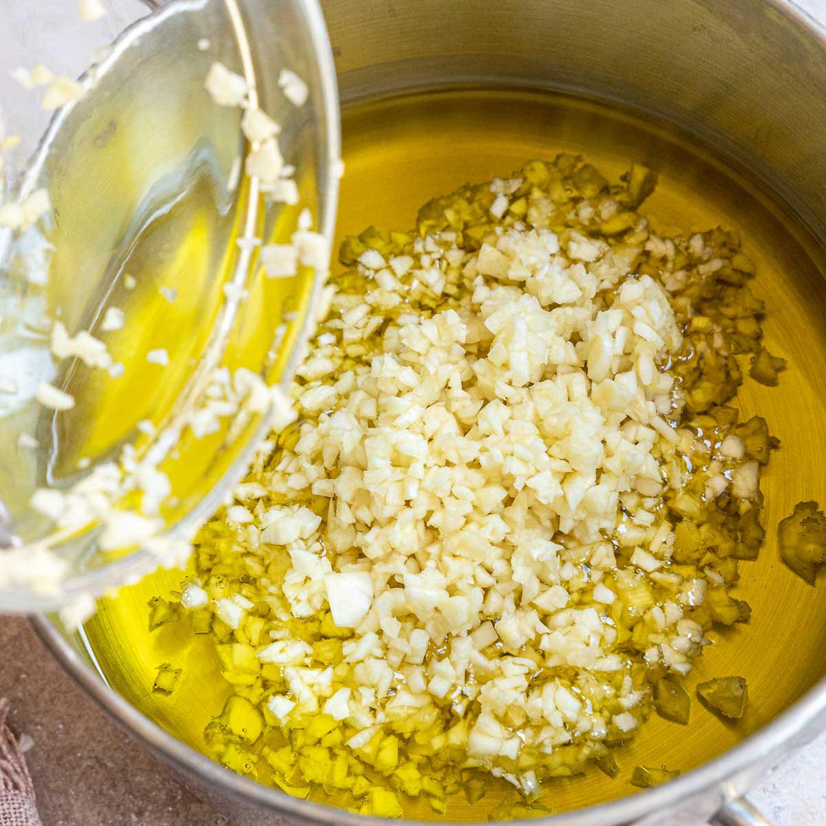 Adding garlic to a sauce pot with oil.