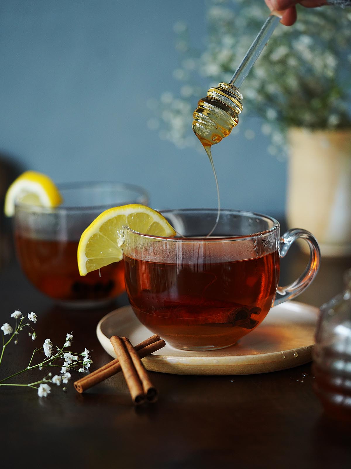 Drizzling the tea in a mug with honey.