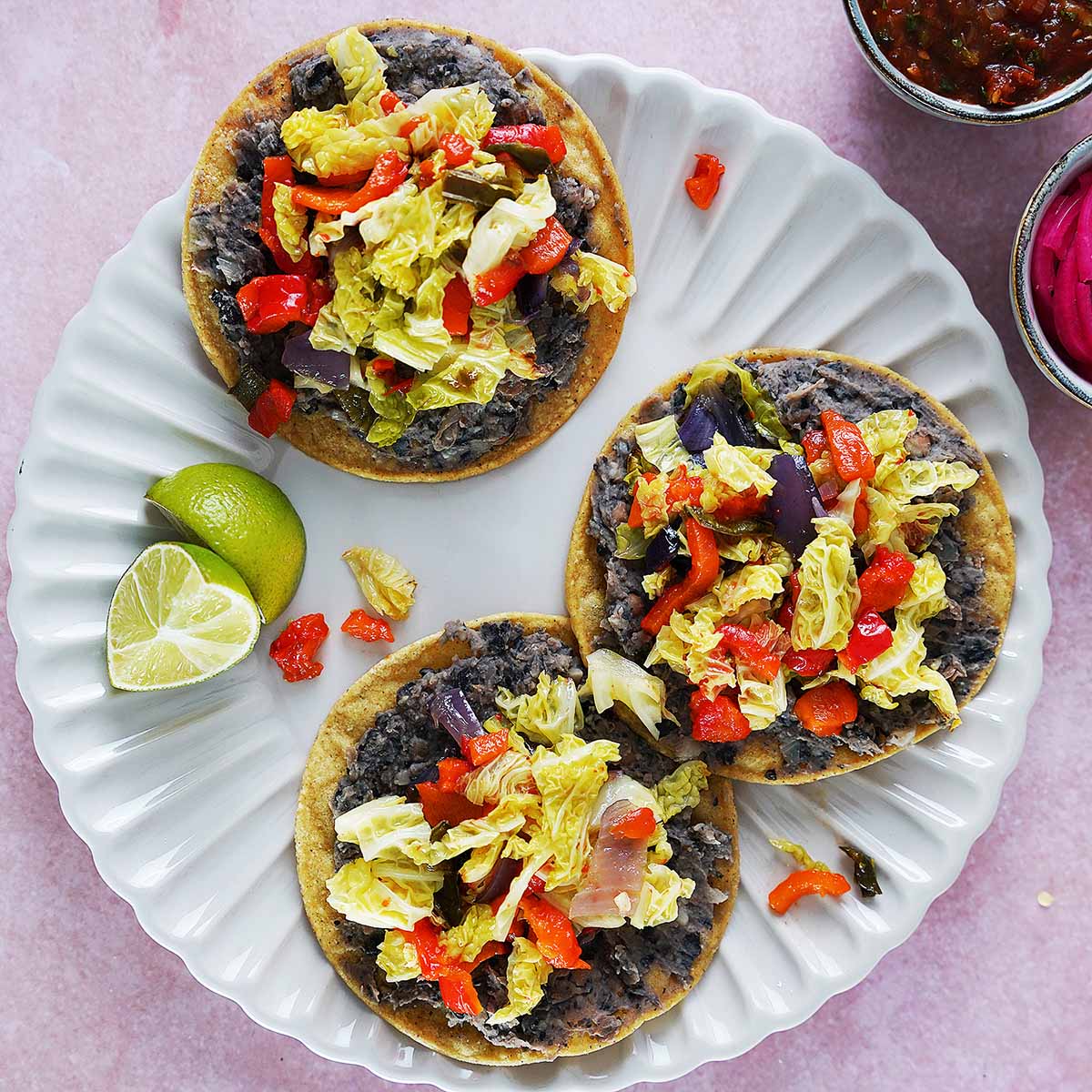 Three corn tostadas loaded with black beans and roasted vegetables.