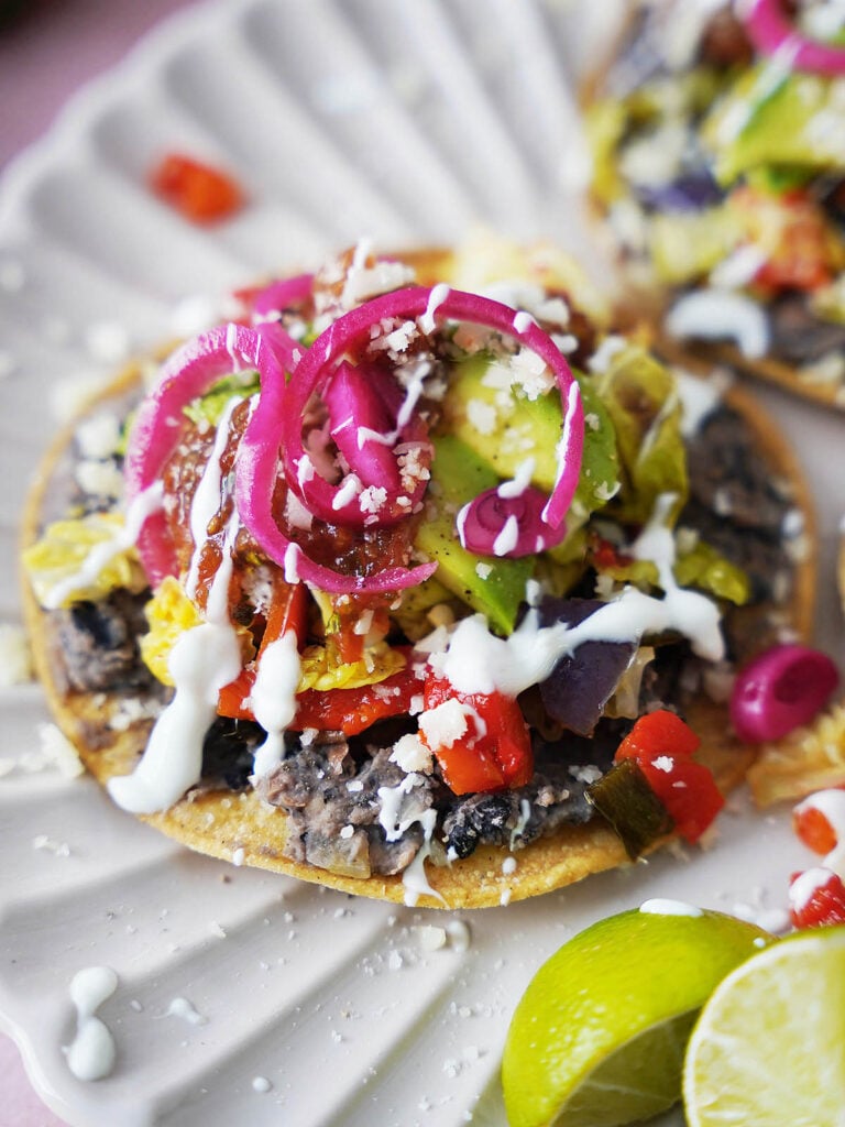 A black bean tostada loaded with veggies and cheese.