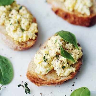 Two small toasts topped with egg salad and garnished with spinach leaves.