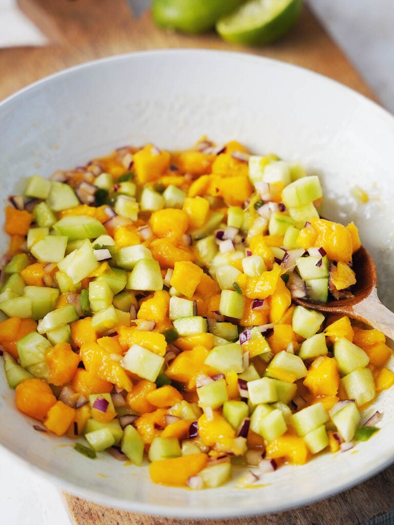 A bowl with mango salsa and cucumber.