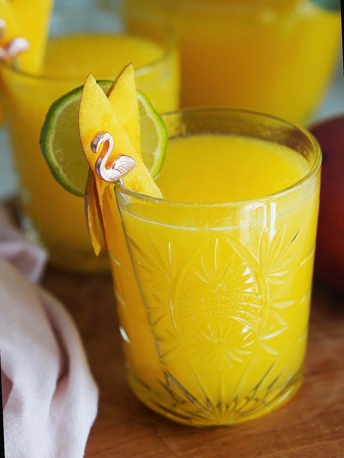 A glass of Agua De Mango in a glass with mango slices as garnish.