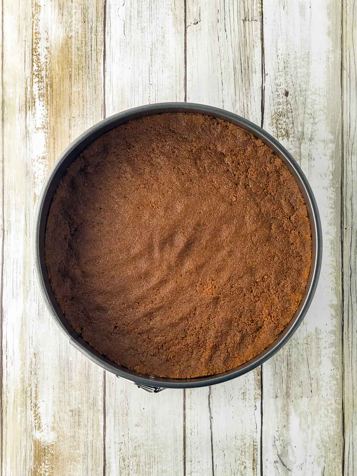 A cake mold with the cookie crust already form in it.