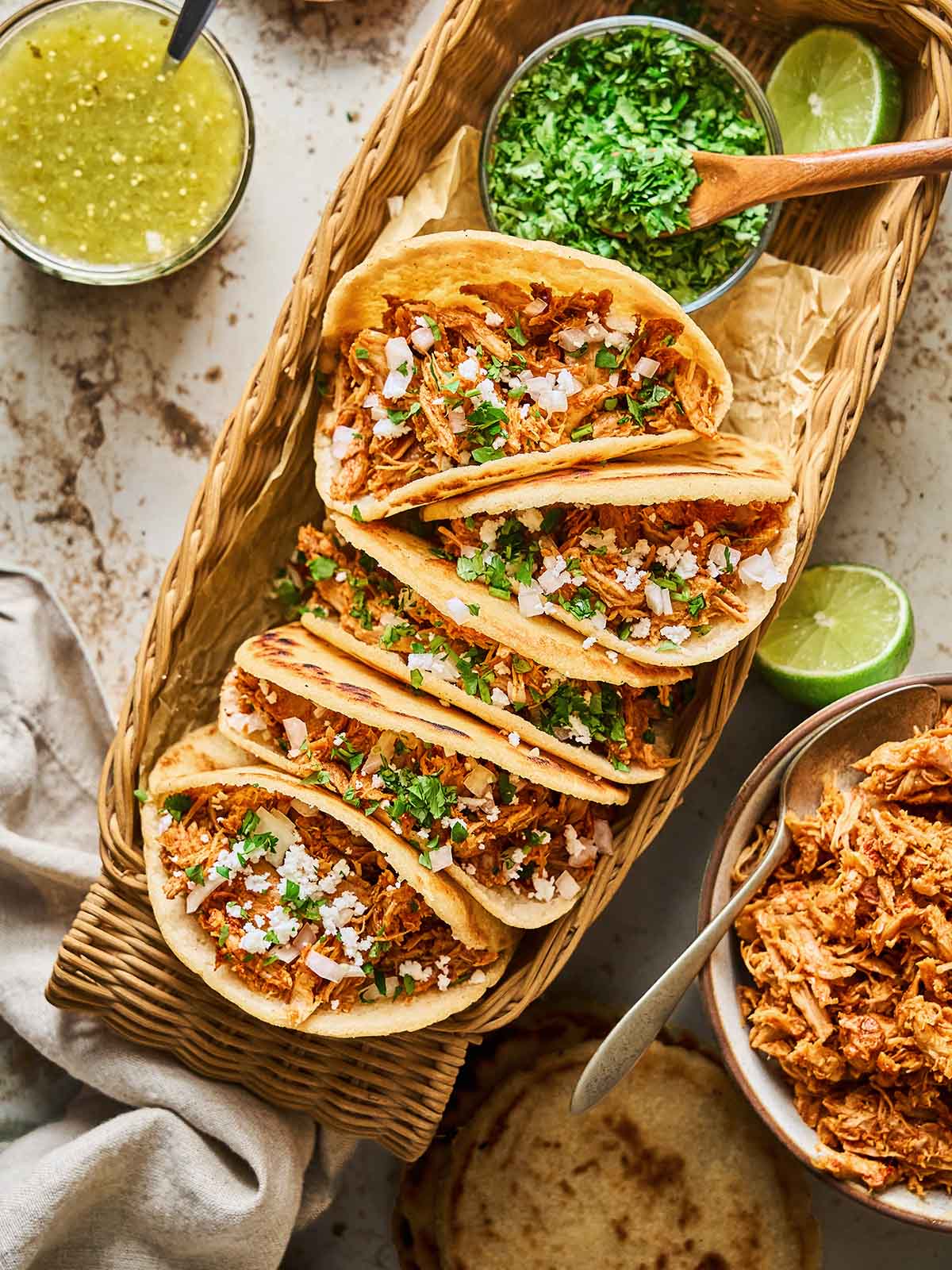 Shredded meat inside gorditas topped with fresh cilantro and onions, served with lime and sides for an authentic Mexican flavor.