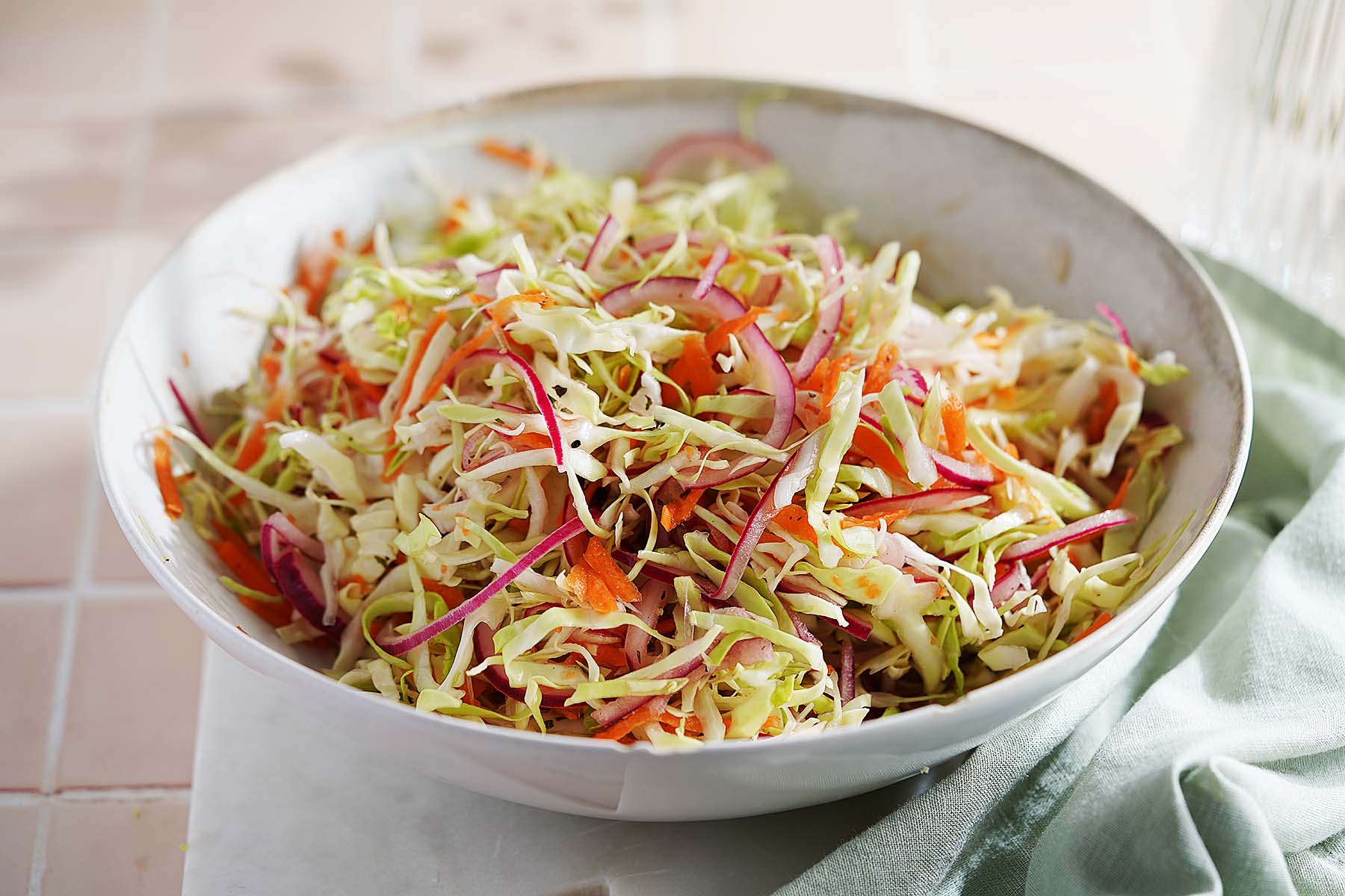 A bowl of curtido made with shredded cabbage, carrots, and red onion.