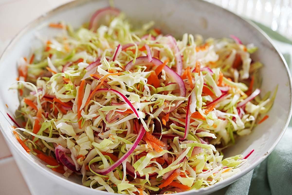 A bowl of Curtido made with shredded cabbage, carrots, and red onion.