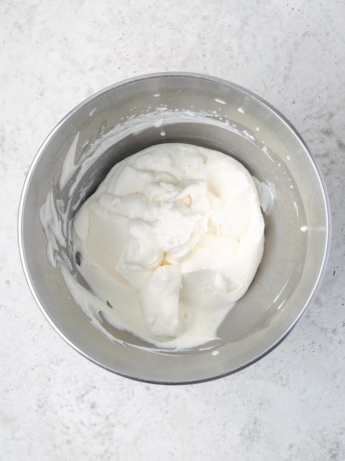 Whipped cream in a stainless steel mixing bowl.