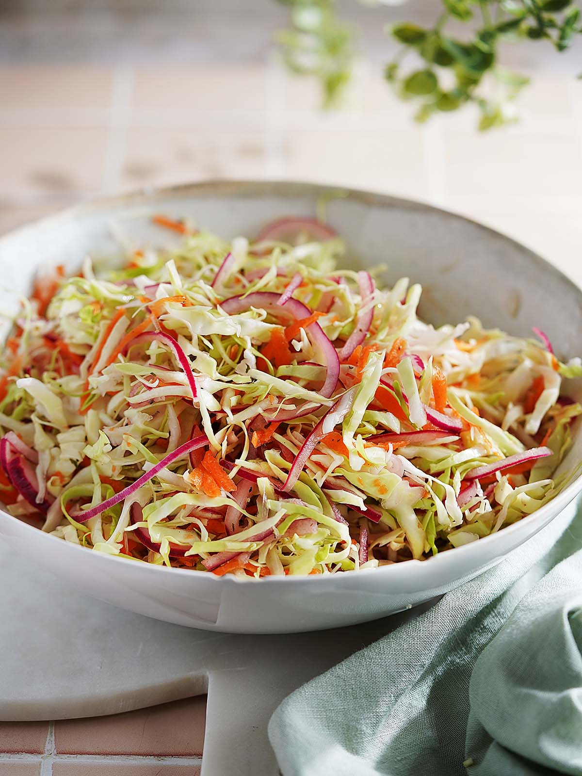 A bowl of coleslaw made with shredded cabbage, carrots, and red onion.
